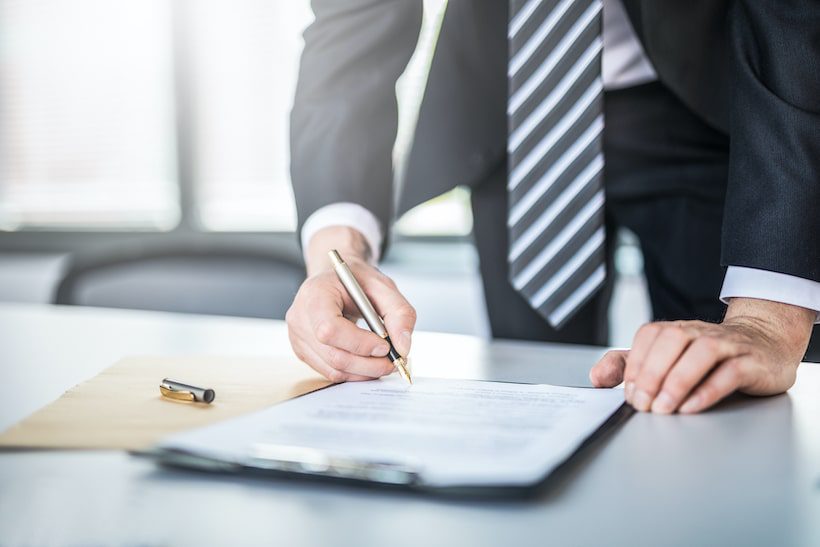 man in a suite signing a document